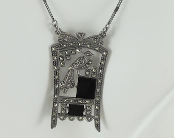 May include: A silver necklace with a black onyx and marcasite pendant featuring a bird design.
