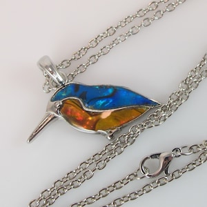 May include: A silver chain necklace with a blue, orange, and iridescent bird pendant.