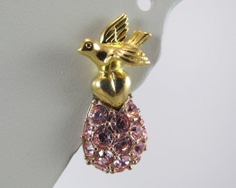 May include: Gold tone earrings with a pink crystal teardrop design. The teardrop is accented with a gold bird and heart.