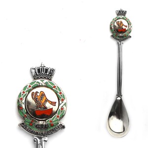 Puede incluir: Cuchara de plata con un diseño de esmalte verde, rojo y naranja que presenta una corona y un pájaro. La cuchara tiene el texto "GTL", "ZAAM", "EN", "HARDE", "KNIK" alrededor del diseño.