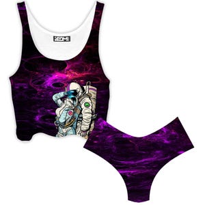 May include: A two-piece set with a white and black crop top and matching bottoms. The set has a purple and black nebula design. The crop top features a graphic of two astronauts embracing. The bottoms are a V-cut style.
