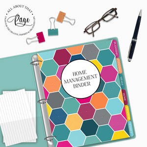 May include: A teal binder with a colorful geometric pattern on the cover. The binder has a silver ring mechanism and tabs labeled "Family", "Finances", "Home", "Meals", "Cleaning", and "Planning". The text "HOME MANAGEMENT BINDER" is printed in a white circle on the cover.