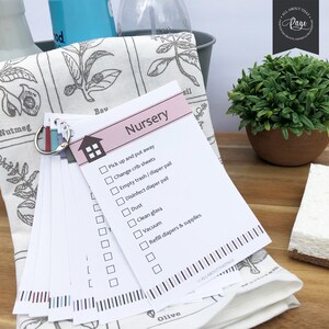 Pu&ograve; includere: Un elenco di controllo rosa con il titolo "Nursery" e un elenco di attivit&agrave; da completare, tra cui "Raccogli e riponi", "Cambia le lenzuola del lettino", "Svuota la spazzatura/il secchio dei pannolini", "Disinfetta il secchio dei pannolini", "Spolvera", "Pulisci il vetro", "Passa l'aspirapolvere" e "Riempi i pannolini e gli accessori".