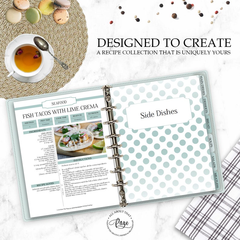 May include: A blue and white polka dot recipe binder with a recipe for Fish Tacos with Lime Crema. The binder has tabs for different categories of recipes, including seafood, side dishes, main dishes, desserts, bread, soups, salads, and meatless.