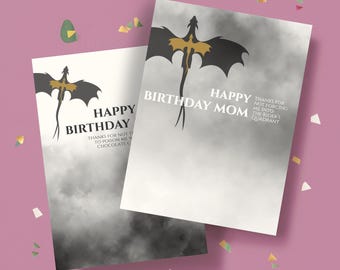May include: Two birthday cards featuring a dragon design. The cards have a white background with a black and gold dragon silhouette. Text on the cards reads "Happy Birthday Mom" and "Thanks for not forcing me into the Rider's Quadrant."