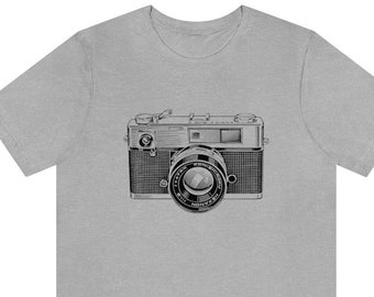 May include: A gray t-shirt with a black and white illustration of a vintage camera.