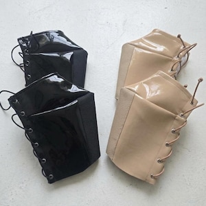 May include: Two pairs of face masks. One pair is black, with a glossy finish and black laces. The other pair is beige, with a glossy finish and beige laces. The masks have a lace-up design.