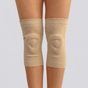 May include: A pair of beige knee sleeves, designed to provide support and compression. The sleeves are made of a stretchy, breathable fabric and feature a contoured design around the knee cap.