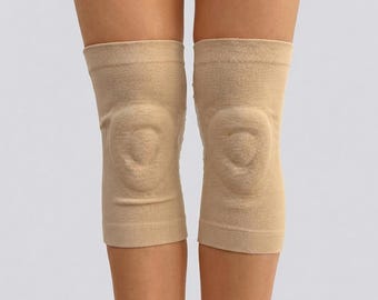 May include: A pair of beige knee sleeves, designed to provide support and compression. The sleeves are made of a stretchy, breathable fabric and feature a contoured design around the knee cap.