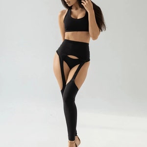 Puede incluir: Un sujetador deportivo negro y unos leggings a juego de cintura alta con un diseño de liguero. Los leggings tienen un detalle de corte en la parte delantera y están hechos de una tela elástica y cómoda.