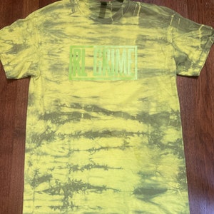 May include: A yellow and green tie-dye t-shirt with the text "RL GRIME" in a green box.