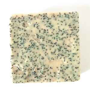 Puede incluir: Una pastilla de jabón cuadrada con una base beige claro y un patrón moteado verde y negro.