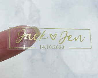 Peut inclure: Autocollant rectangulaire transparent avec inscription dorée. L'autocollant indique "Jack ♥ Jen" et "14.10.2023".