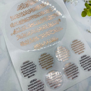 May include: A set of gold foil stickers with Arabic calligraphy. The stickers are circular and feature different sizes. The largest sticker is about 6 inches in diameter.