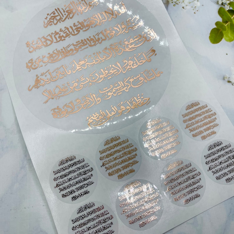May include: A set of gold foil stickers with Arabic calligraphy. The stickers are circular and feature different sizes. The largest sticker is about 6 inches in diameter.