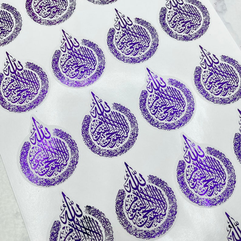 May include: A collection of purple stickers featuring Arabic calligraphy. Each sticker has a teardrop shape with intricate script within a circular border. The stickers are arranged on a white surface, creating a pattern.