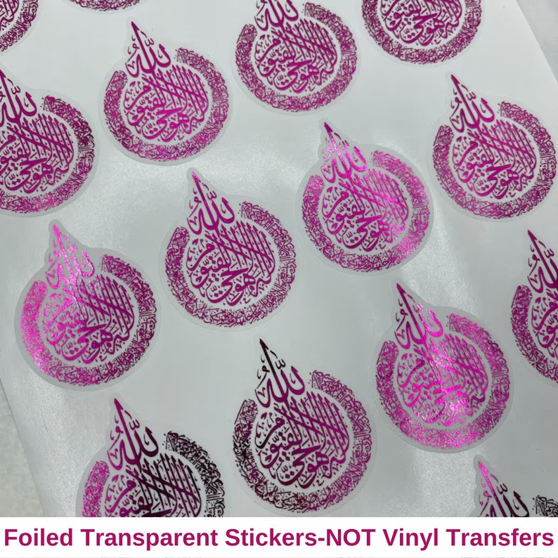 May include: Sheet of transparent stickers with a pink foil finish. Each sticker features ornate calligraphy in a circular design with a teardrop shape at the top. The stickers are arranged on a white background.