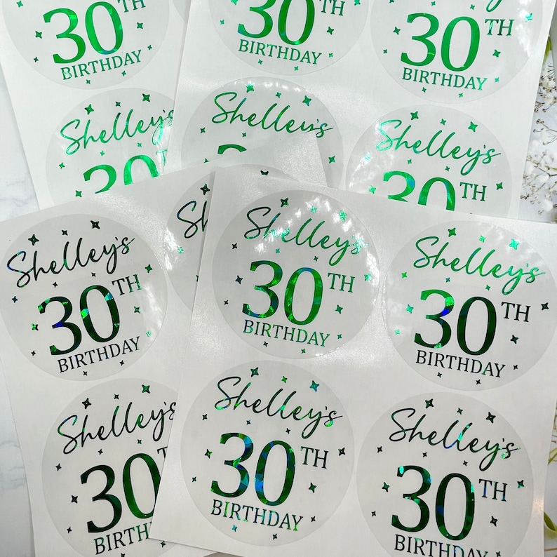 May include: A set of 10 clear, round stickers with a green holographic finish. The stickers feature the text "Shelley's 30th Birthday" with a green number 30 and small stars.