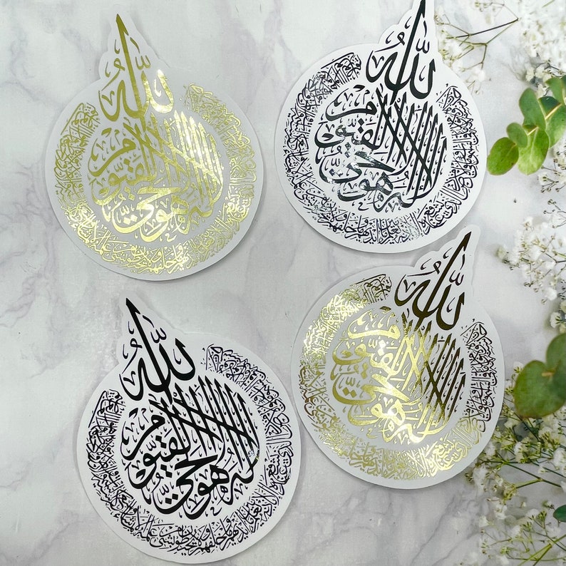 May include: Four circular stickers with Arabic calligraphy in gold and black. The stickers have a white background and a unique teardrop shape at the top. The calligraphy is intricate and detailed, with a decorative border.
