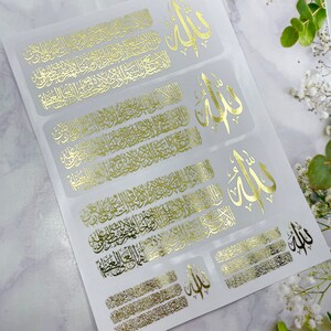 May include: A sheet of adhesive stickers featuring gold foil Arabic calligraphy. The design includes repeating rectangular blocks of intricate script alongside the word Allah in a stylized font. The stickers are arranged on a white backing.