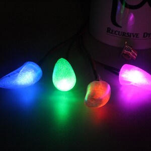 Pu&ograve; includere: Una stringa di quattro luci colorate e luminose. Le luci hanno la forma di gocce e emettono luce blu, verde, arancione e viola. Le luci sono collegate da fili sottili.
