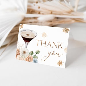 May include: A white rectangular thank you card featuring a watercolor illustration of a martini glass, beige and white flowers, green eucalyptus leaves, and scattered autumn leaves. The text THANK you is printed in a brown serif and script font.