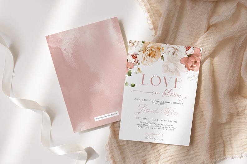 May include: Two blush-colored cards, one with a floral design and the text "LOVE in bloom" for a bridal shower. The other card has a watercolor wash. The cards are on a white surface with a ribbon and fabric.