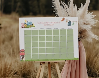 May include: A white calendar with the text "GUESS BABY WEBBER'S BIRTHDAY" and a grid for tracking dates. The calendar features illustrations of a tractor, farm animals, and baby clothes. It is displayed on a wooden easel.
