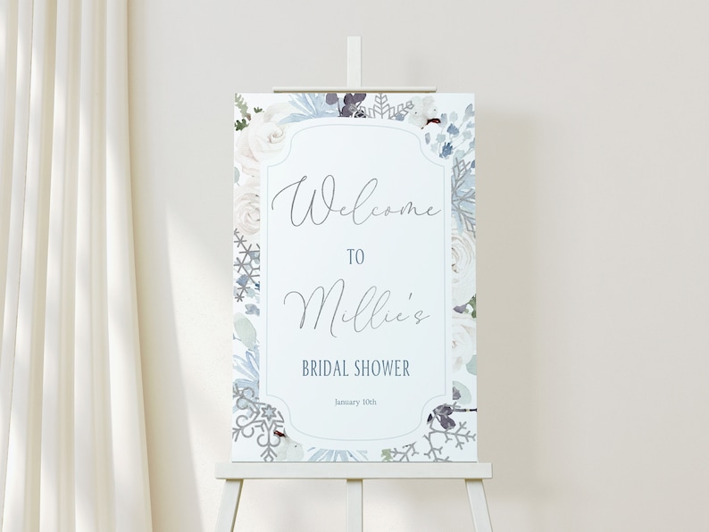 May include: A bridal shower welcome sign with a floral design in white and blue hues. The sign says "Welcome to Millie's Bridal Shower" and the date is January 10th. It is displayed on a white easel, suitable for a wedding.