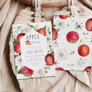 Może przedstawiać: Białe zaproszenie na baby shower z ilustracją czerwonego jabłka i tekstem "APPLE of our eye" i "Kaylin Russel". Zaproszenie ma białe tło z czerwonymi jabłkami, białymi kwiatami i zielonymi liśćmi.