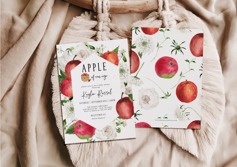 Może przedstawiać: Białe zaproszenie na baby shower z ilustracją czerwonego jabłka i tekstem "APPLE of our eye" i "Kaylin Russel". Zaproszenie ma białe tło z czerwonymi jabłkami, białymi kwiatami i zielonymi liśćmi.