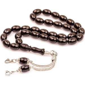 Peut inclure: Un collier de prière en perles noires avec un pompon argenté et un manche en bois.