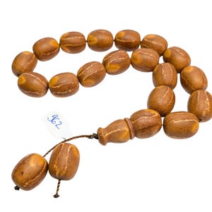 May include: A brown wooden prayer beads or rosary with a tassel. The beads are oval shaped and have a light brown and dark brown pattern. The tassel is made of brown string.