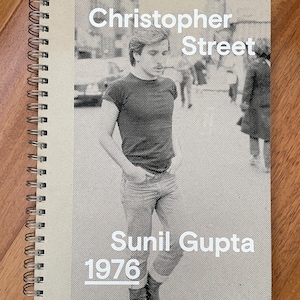 May include: A spiral-bound notebook with a black and white photograph on the cover. The cover features the text "Christopher Street" above a photo of a man in a t-shirt and jeans. Below the photo is the text "Sunil Gupta 1976".