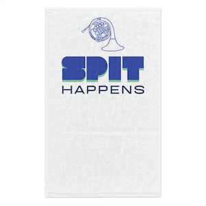 May include: White hand towel with the text "SPIT HAPPENS" in blue and green block letters. A blue French horn graphic is above the text. The towel is a rectangular shape.