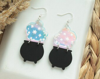 May include: A pair of iridescent earrings featuring a black cauldron with a swirling cloud of iridescent stars above it.