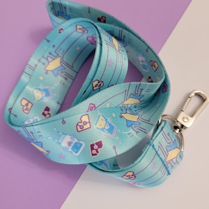 May include: A light blue lanyard with a repeating pattern of circuit boards, stars, and cartoon robots. The lanyard has a silver metal clasp.