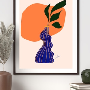 Puede incluir: Impresión artística abstracta. Un jarrón azul con líneas doradas sostiene hojas verdes, sobre un fondo naranja. La obra está enmarcada en un marco negro y firmada. El tema es moderno y minimalista. Medidas en cm.