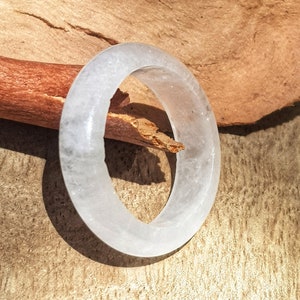 May include: A white, opaque, round bangle bracelet made of polished stone. The bangle is smooth and has a glossy finish.