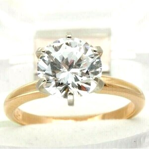 Könnte beinhalten: Ein goldener Ring mit einem großen, klaren, runden Diamanten.