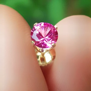 May include: A pink gemstone earring with a gold setting.