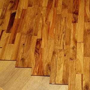 Könnte beinhalten: Eine Nahaufnahme eines Holzbodens aus rechteckigen Holzstücken unterschiedlicher Größe. Das Holz ist hellbraun mit einer natürlichen Maserung.