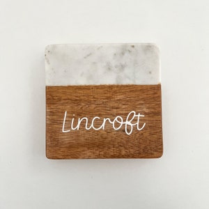 Op de afbeelding: Een serveerplank van wit marmer en hout met de naam "Lincroft" in witte letters.