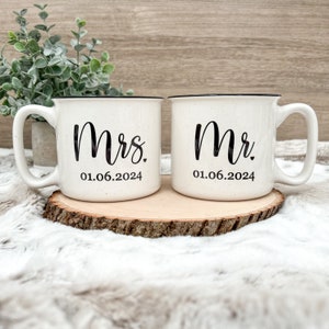 Puede incluir: Dos tazas de cer&aacute;mica blanca con bordes negros y letras negras. La taza de la izquierda dice "Mrs. 01.06.2024" y la taza de la derecha dice "Mr. 01.06.2024".