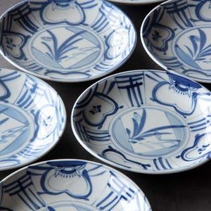 Könnte beinhalten: Satz von sechs blauen und weißen Keramiktellern mit Blumenmuster. Die Teller haben einen erhöhten Rand und einen gewellten Rand.