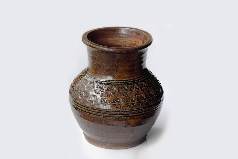 K&ouml;nnte beinhalten: Eine braune Keramikvase mit einem dekorativen Sternmuster und einer dunkelbraunen Glasur.