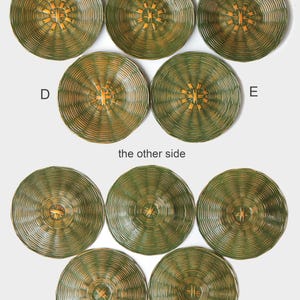May include: A collection of woven, circular placemats in shades of green and gold. The placemats have a radial design with a central starburst pattern. The image shows both sides of the placemats, with the text "the other side" visible.