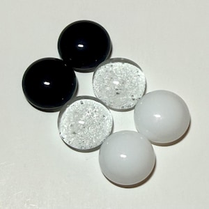 May include: Six glass marbles in a variety of colors. Two are solid black, two are clear with small air bubbles, and two are solid white. The marbles are arranged in a circular pattern.