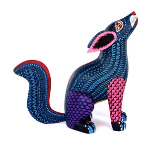 May include: A hand-painted wooden coyote figurine featuring a dark blue body covered in intricate white geometric patterns. The sculpture has a pink and black checkered front leg, a purple checkered hind leg, and a red-trimmed curved tail.