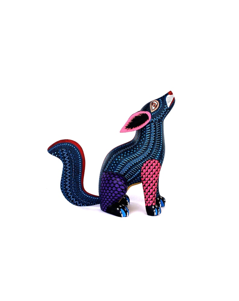 May include: A hand-painted wooden coyote figurine featuring a dark blue base color with intricate white dot patterns, pink ears, a purple checkered hind leg, and a pink checkered front leg, depicted in a seated position with its head tilted upward.